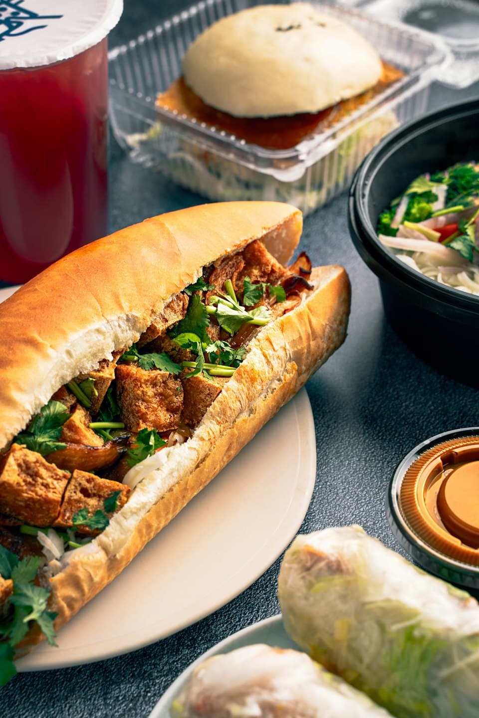 Vietnamese takeout food laid out, including banh mi, noodles, and spring rolls.