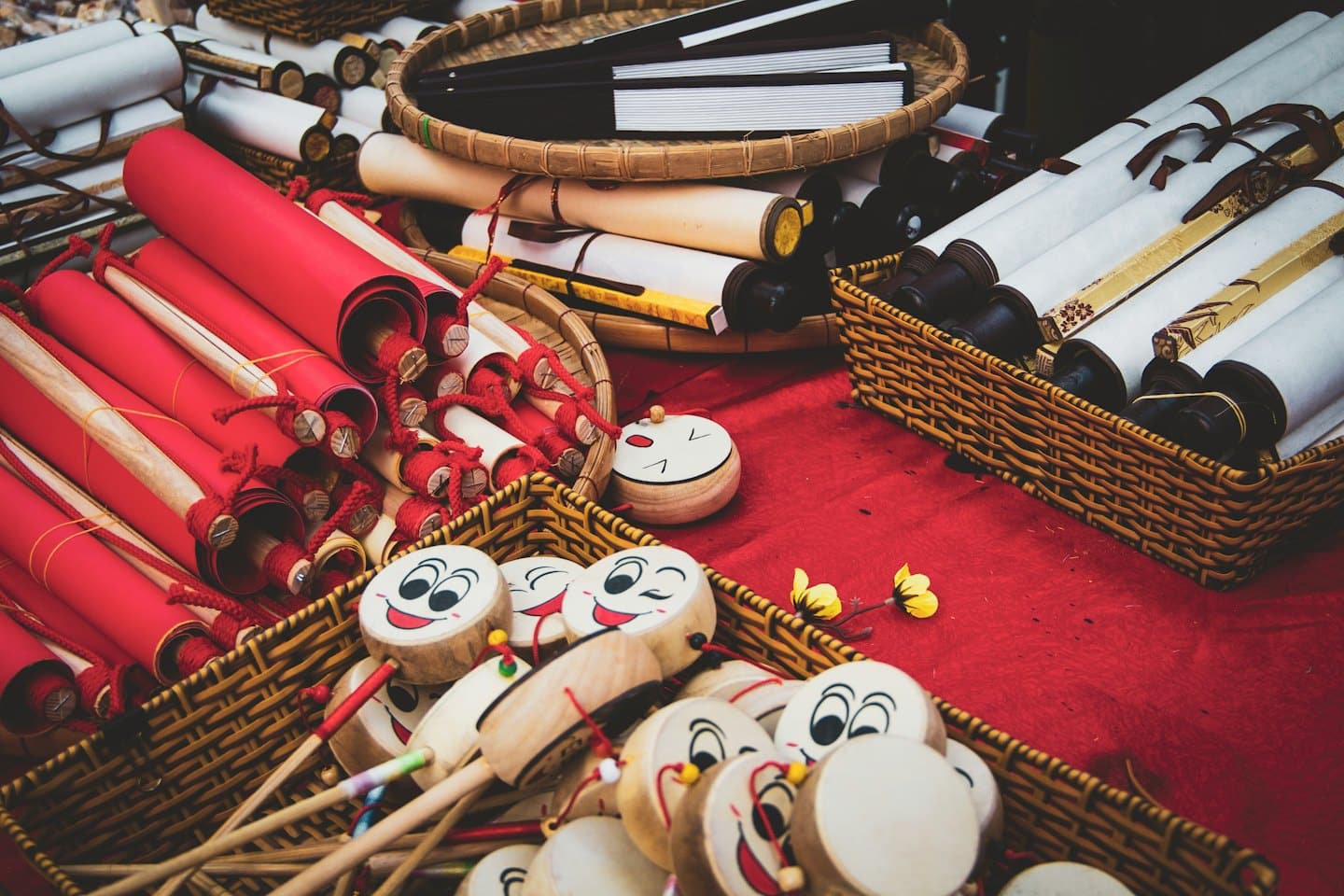 Traditional scrolls, drums, and folding fans displayed on a market stall.