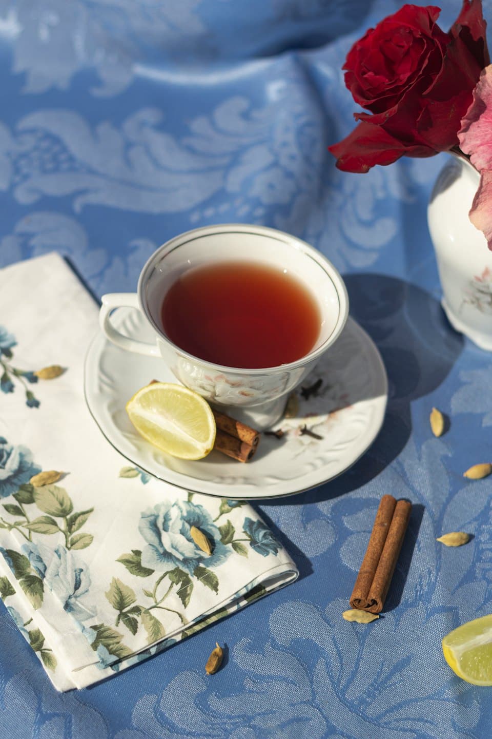 Spiced tea with lemon and cinnamon sits on a floral saucer.