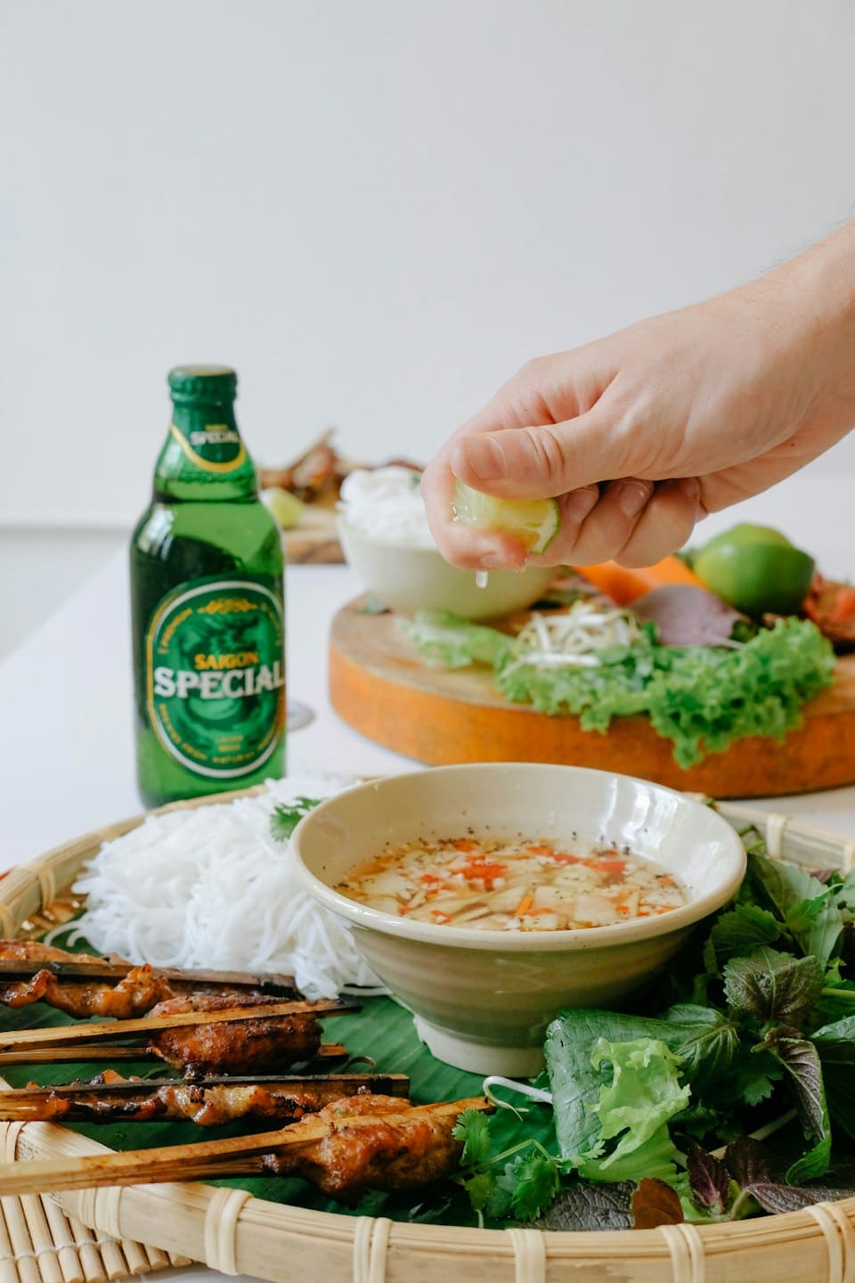 Hand squeezes lime into Vietnamese dipping sauce at meal.